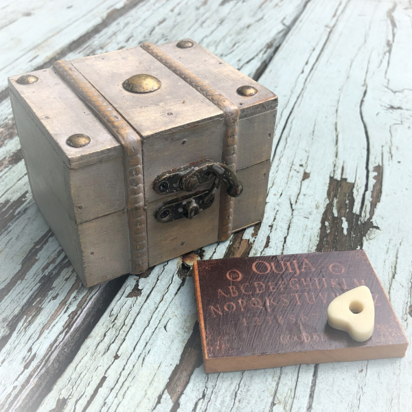 Miniature treasure chest with wood Ouija board and planchette inside mirror